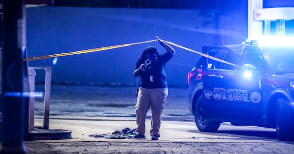 An Atlanta police crime scene technician works the scene at the Exxon Food Mart on Joseph E. Boone Boulevard.