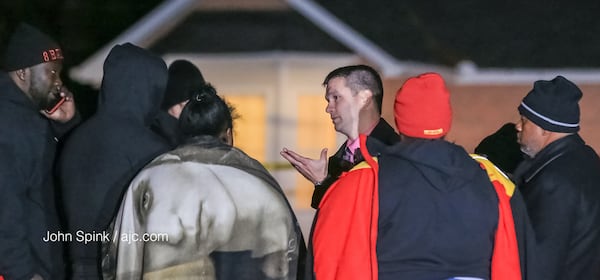 Atlanta police detectives speak with family members outside a home where two people were found dead.  JOHN SPINK / JSPINK@AJC.COM