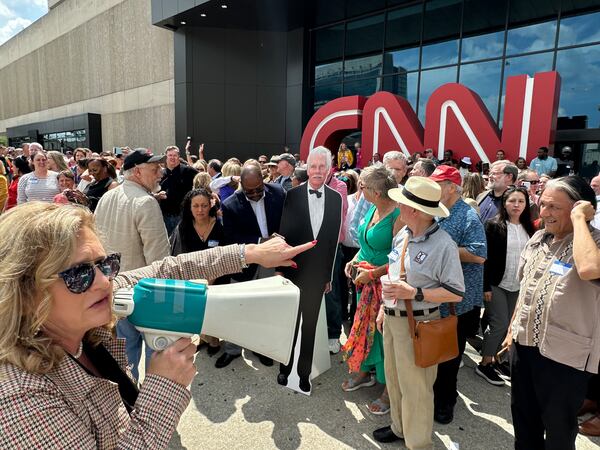 CNN alum Marylynn Ryan, organizer of the CNN Center farewell photo and reception, uses a bullhorn to corral the troops before the photo shoot on June 1, 2023, the 43rd anniversary of CNN's launch. Ted Turner wasn't there but a cardboard cutout of him was. RODNEY HO/rho@ajc.com