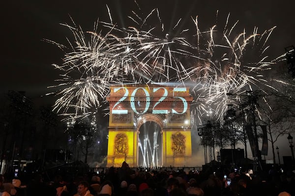 A light show is projected on the Arc de Triomphe as fireworks explode during New Year celebrations on the Champs Elysees in Paris, France, Wednesday, Jan. 1, 2025. (AP Photo/Thibault Camus)