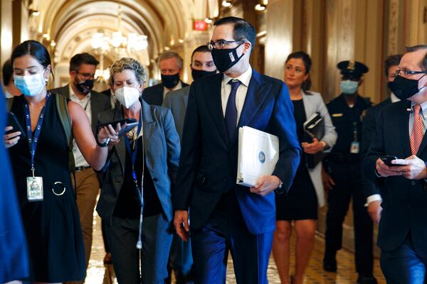 Treasury Secretary Steven Mnuchin , center, walks to a Republican luncheon, Tuesday, July 21, 2020, while attending meetings on Capitol Hill in Washington. In the background at center left is White House Chief of Staff Mark Meadows. (AP Photo/Jacquelyn Martin)