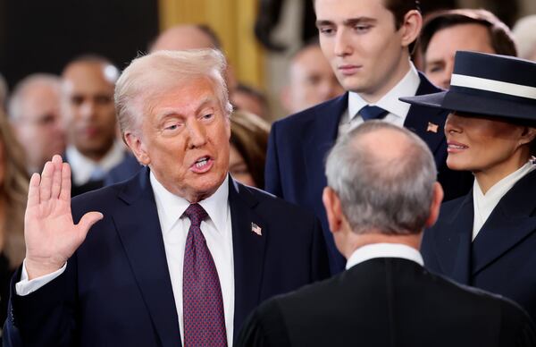 President Donald Trump takes the oath of office as son Barron Trump and wife Melania Trump look on. 