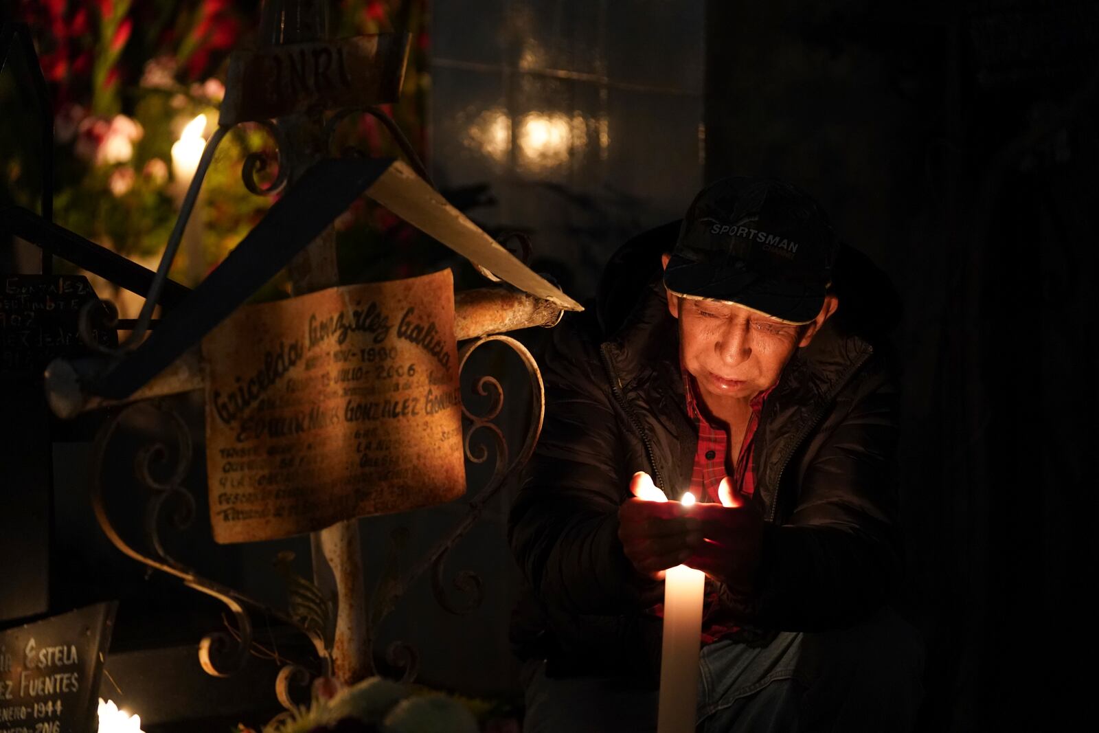 A man sits at the tomb of a dearly departed celebrating the Day of the Dead, at the San Gregorio Atlapulco cemetery on the outskirts of Mexico City, Friday, Nov. 1, 2024. (AP Photo/Moises Castillo)