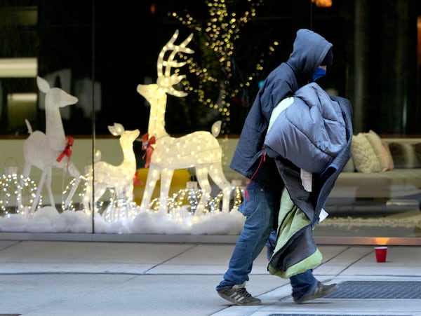 A man carries blankets as an Arctic blast brings single-digit temperatures with wind chills below zero on Thursday, Dec. 12, 2024, in Chicago. (AP Photo/Charles Rex Arbogast)