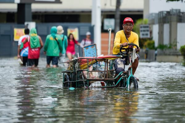 A man navigates flooded streets caused by Tropical Storm Trami on Friday, Oct. 25, 2024, in Cainta, Rizal province, Philippines. (AP Photo/Aaron Favila)