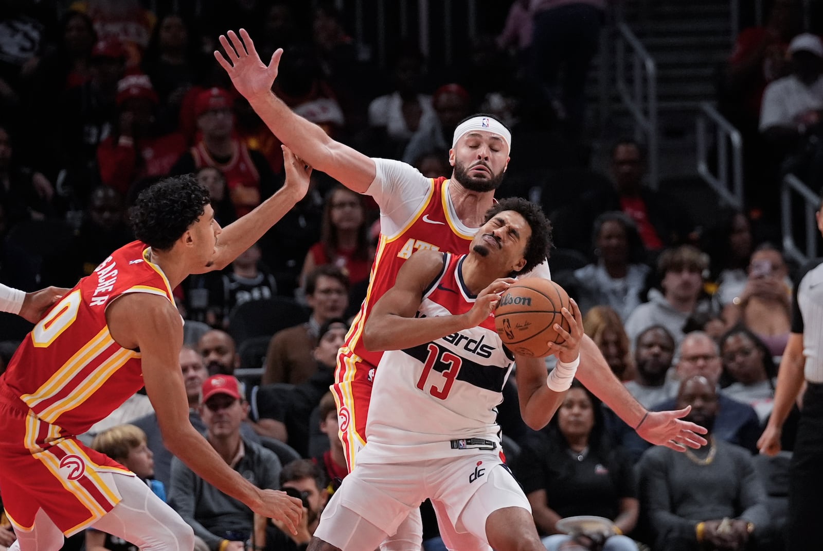 Washington Wizards guard Jordan Poole (13) is fouled by Atlanta Hawks forward Larry Nance Jr. (22) during the first half of an NBA basketball game Monday, Oct. 28, 2024, in Atlanta. (AP Photo/ John Bazemore)