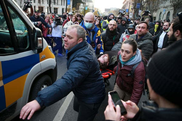 Demonstrators and paramedics carry a wounded person to an ambulance after clashes with police during a rally against the results of the parliamentary elections amid allegations that the vote was rigged in Tbilisi, Georgia, on Tuesday, Nov. 19, 2024. (AP Photo/Zurab Tsertsvadze)