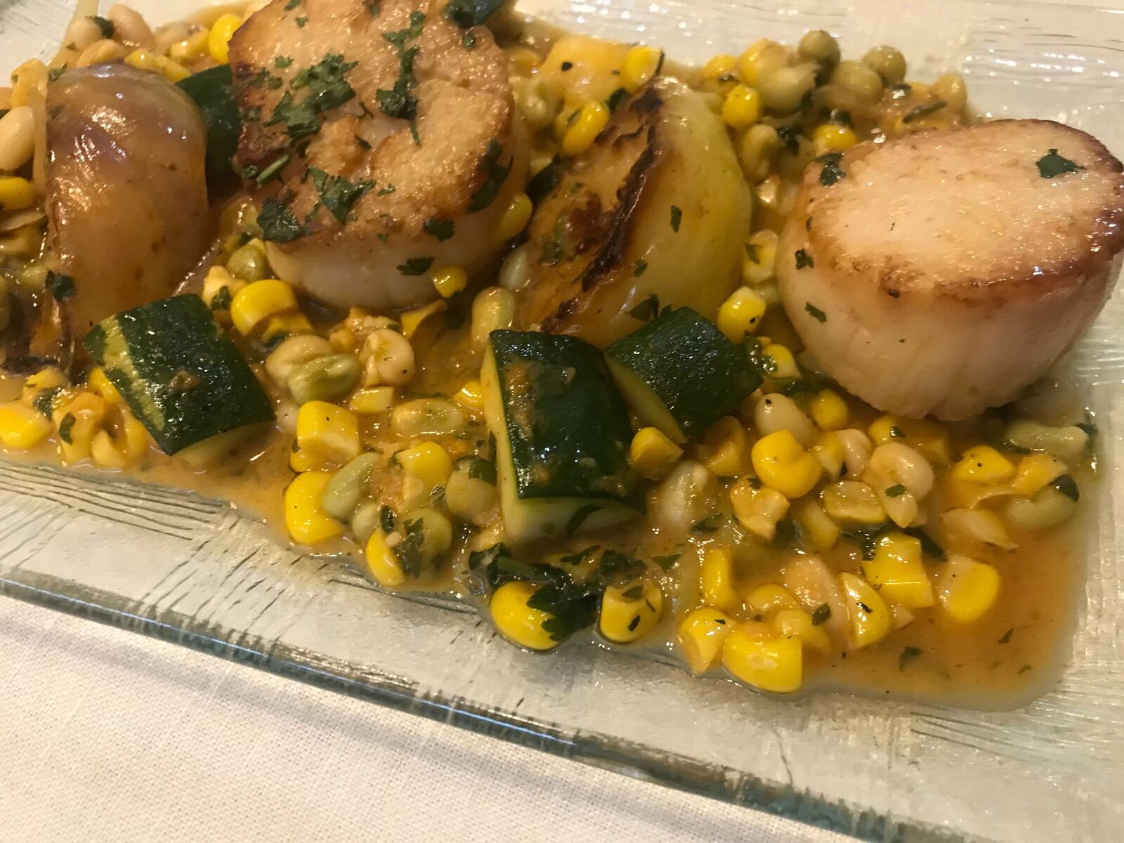 An appetizer of pan-roasted scallops from Aix sits on a bed of summer succotash. LIGAYA FIGUERAS / LIGAYA.FIGUERAS@AJC.COM