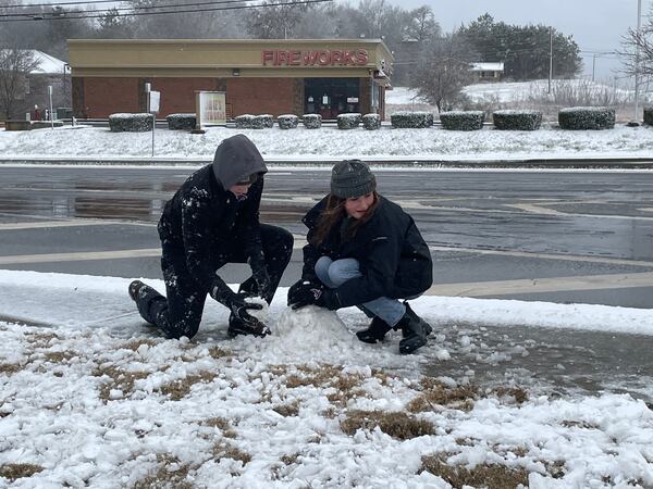 Raymond Clark, left, and Alayna Zolman build a snowman at a QT service station off I-985, The family drove nearly 100 miles Sunday to see some snow. Photo by Bill Torpy