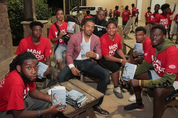 Benjamin Raymond gifts boys attending the ninth annual Steve Harvey Mentoring Program for Young Men National Camp with his book, “Playing the Game Without a Coach,” an autobiographical sketch of his life growing up without his father and with a drug-addicted mother. Raymond, who went on to become a successful entrepreneur, is a regular speaker and mentor to boys at the camp. CONTRIBUTED BY ITORO UMONTUEN