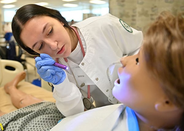 One reason GGC nursing graduates had a 100% pass rate in 2024 was the use of “flipped classrooms.” Students took classes online and then applied what they learned in the college’s modern basic skills and simulation labs. GGC nursing student Jenna Phelps checks the nursing manikin's mouth to confirm the feeding tube was inserted correctly. Photo by Daniel Melograna/Georgia Gwinnett College.