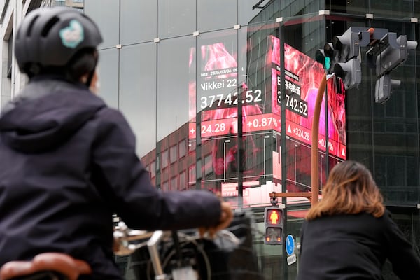 FILE - People stand in front of an electronic stock board showing Japan's Nikkei index at a securities firm Thursday, March 6, 2025, in Tokyo. (AP Photo/Eugene Hoshiko,File)