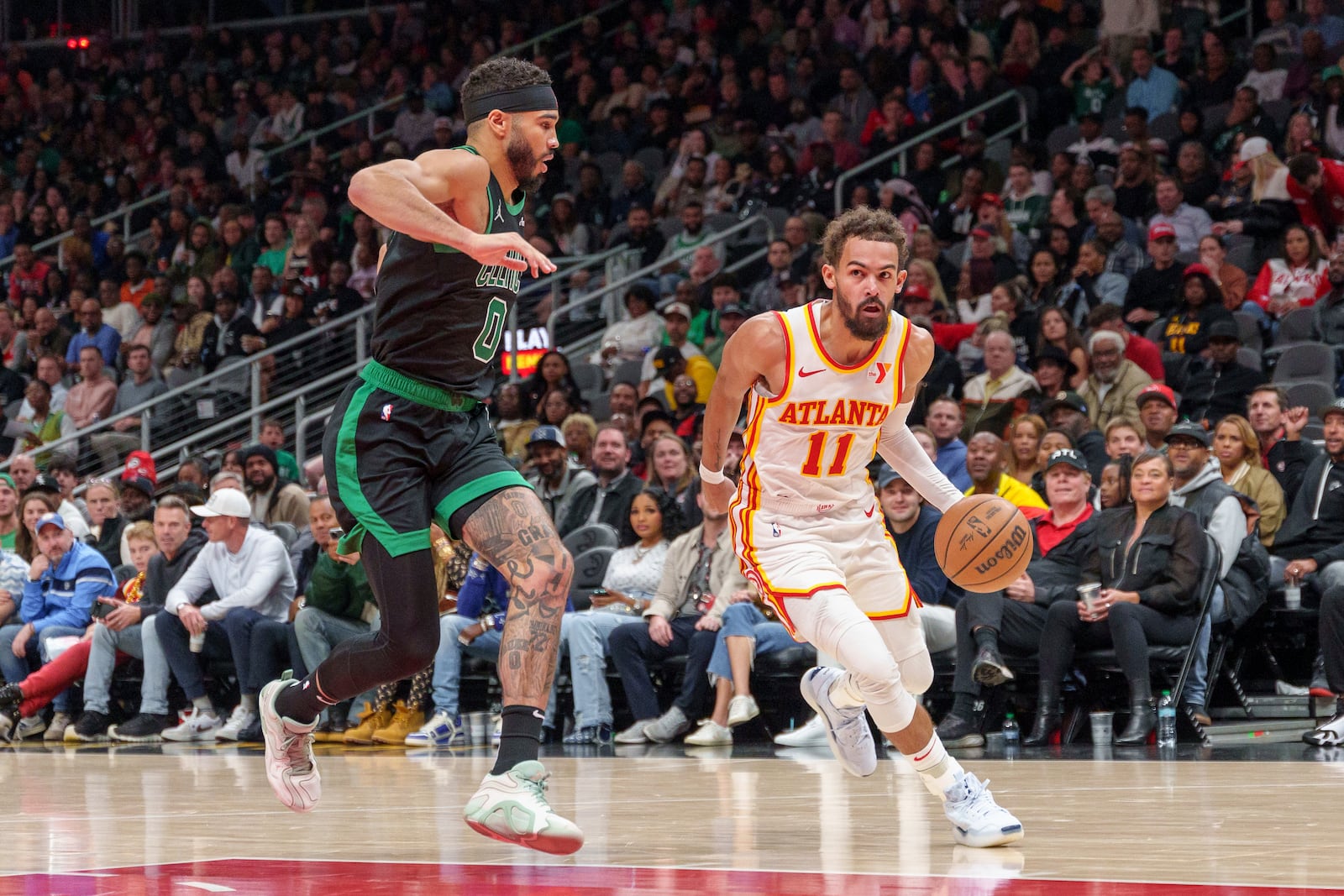 Atlanta Hawks guard Trae Young (11) drives the lane while guarded by Boston Celtics forward Jayson Tatum (0) during the first half of an NBA basketball game, Monday, Nov. 4, 2024, in Atlanta. (AP Photo/Jason Allen)