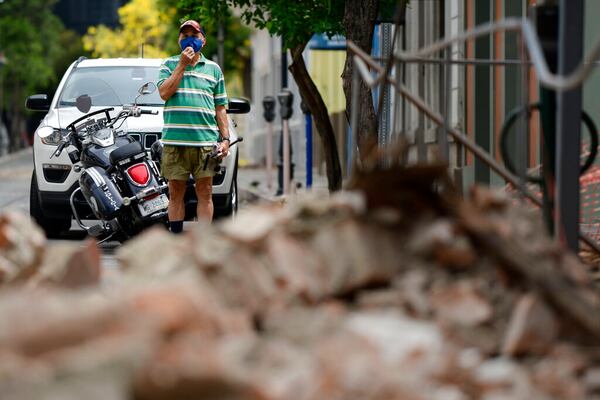 A resident wears a protective face mask as a precaution against the spread of the new coronavirus as he looks at damage caused by a 5.4-magnitude earthquake, in Ponce, Puerto Rico, Saturday, May 2, 2020. The quake hit near southern Puerto Rico, jolting many from their beds on an island where some people still remain in shelters from previous quakes earlier this year. (AP Photo/Carlos Giusti)