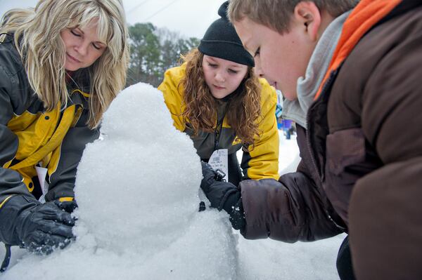 December 21, 2014 Stone Mountain - Stephanie Basile (left) builds a snowman with her grandchildren Savanna and C.J. Simpson during Snow Mountain at Stone Mountain Park on Sunday, December 21, 2014. This is the seventh season that the main lawn at the park has been transformed into a winter wonderland. JONATHAN PHILLIPS / SPECIAL