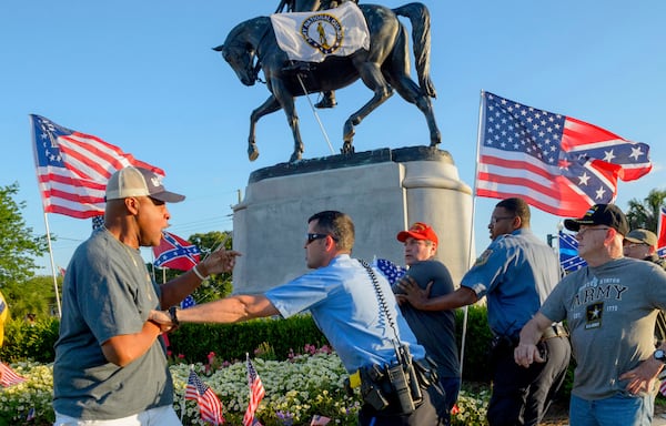 New Orleans Police separate two men after the two tussled, at the Gen. P.G.T. Beauregard monument in City Park in New Orleans, La. Tuesday, May 16, 2017. Workers in New Orleans took down a Confederate monument to Gen. P.G.T. Beauregard early Wednesday. (Matthew Hinton/The Advocate via AP)