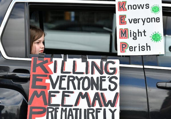 An 8-year-old watches her mother decorate her car before a drive-by protest against Gov. Kemp's decision to reopen some Georgia businesses on April 24, 2020. Over the next 30 days, the number of COVID-19 deaths in Georgia would more than double. (Hyosub Shin / Hyosub.Shin@ajc.com)