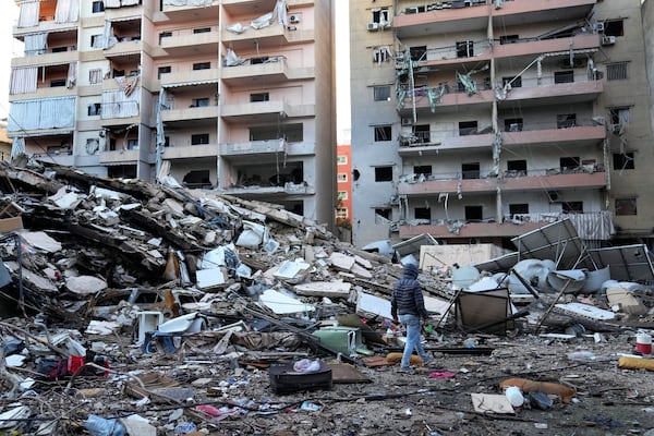 A man passes in front of destroyed buildings that were hit in an Israeli airstrike in Dahiyeh, in the southern suburb of Beirut, Lebanon, Thursday, Nov. 14, 2024. (AP Photo/Hussein Malla)