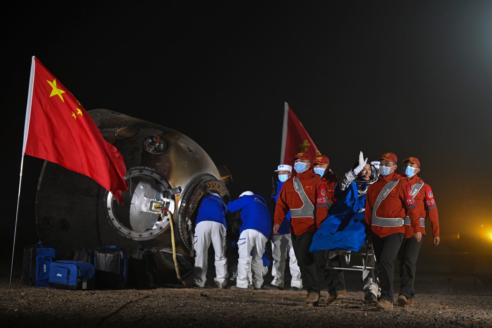 In this photo released by Xinhua News Agency, astronaut Li Cong waves as he is carried out of the re-entry capsule of the Shenzhou-18 manned space mission after it landed successfully at the Dongfeng landing site in northern China's Inner Mongolia Autonomous Region in the early Monday, Nov. 4, 2024. (Lian Zhen/Xinhua via AP)