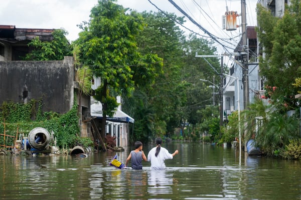 Residents walk along the flooded village caused by Tropical Storm Trami on Friday, Oct. 25, 2024, in Cainta, Rizal province, Philippines. (AP Photo/Aaron Favila)