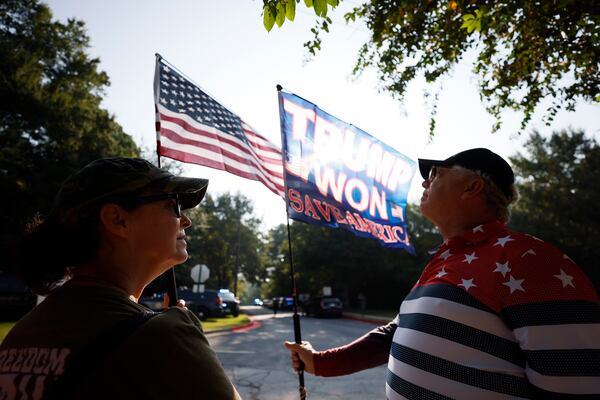 Cliff and Georgina Mac Morris from Maple, Florida, stand outside the Fulton County Jail showing their flags. Later Thursday, Trump is expected to be booked. (Miguel Martinez /miguel.martinezjimenez@ajc.com)