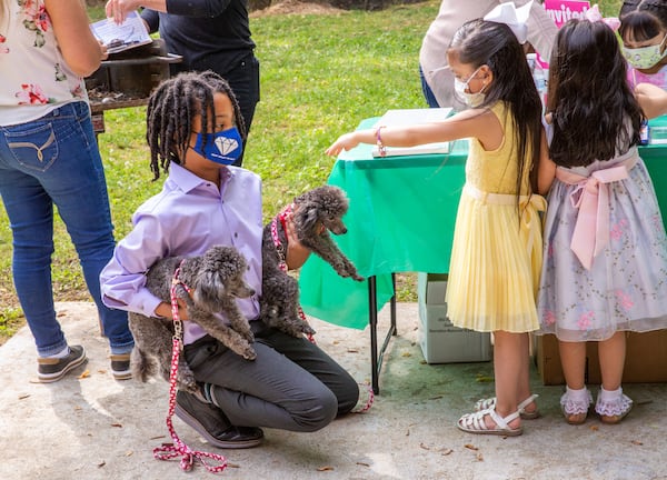 Young philanthropist, 11-year-old Malon James, left, introduces Chachi and Tutu at a Families First event in Norcross where he is giving away quality masks for free Thursday, April 29, 2021.  The non-profit organization has received grant funding and is serving underprivileged communities.  (Jenni Girtman for The Atlanta Journal-Constitution)