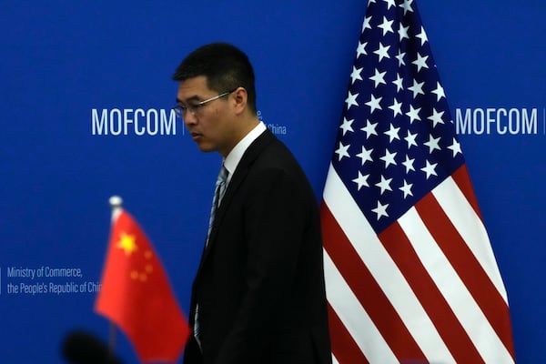 FILE - A Chinese official walks by the China and U.S. national flags before a meeting between Commerce Secretary Gina Raimondo and Chinese Minister of Commerce Wang Wentao at the Ministry of Commerce in Beijing on Aug. 28, 2023. (AP Photo/Andy Wong, Pool, File)