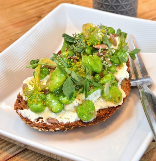 The spring toast, layered with citrusy white cheese, fried favas, green-onion vinaigrette and little flowers and leaves, is one of the dishes that cast a spell at the Expat. CONTRIBUTED BY CHRIS HUNT PHOTOGRAPHY