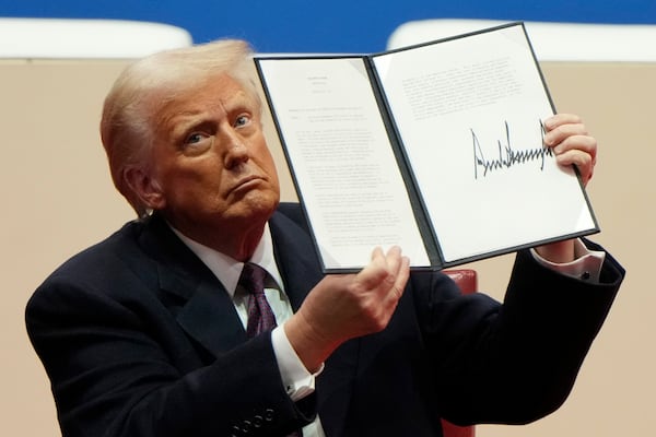 President Donald Trump holds up an executive order after signing it at an indoor Presidential Inauguration parade event in Washington, Monday, Jan. 20, 2025. (AP Photo/Matt Rourke)