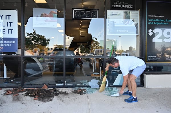 Stephen Davis cleans up at Relax the Back in Buckhead after looters damaged the store's front window.