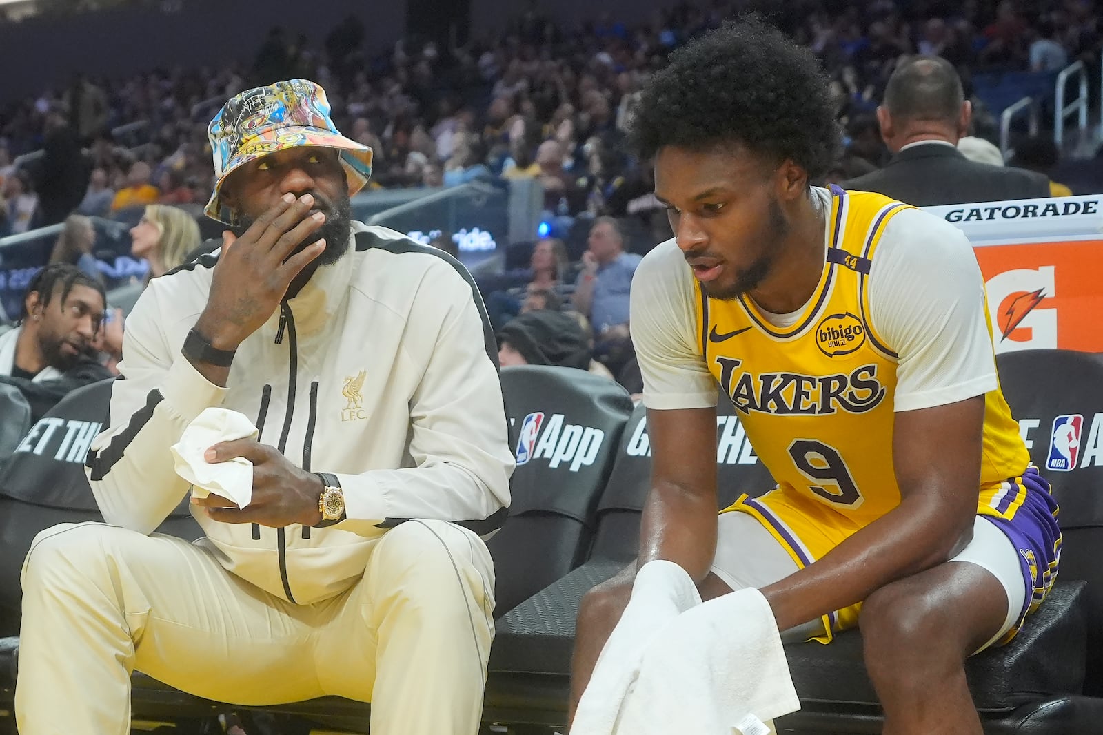 Los Angeles Lakers forward LeBron James, left, talks with guard Bronny James during the second half of an NBA preseason basketball game against the Golden State Warriors in San Francisco, Friday, Oct. 18, 2024. (AP Photo/Jeff Chiu)