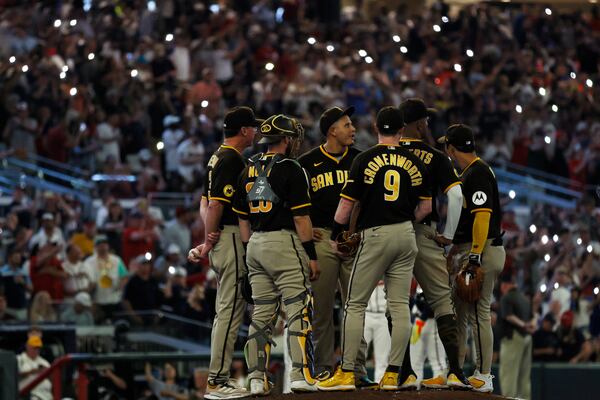 Braves fans light up Truist Park with their cell phones as the Padres confer on the mound. Miguel Martinez /miguel.martinezjimenez@ajc.com