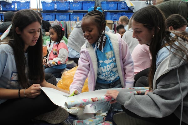 Nola Kennybrew, 5, helps her mentors Sydney Hughes (left) and Samantha Narissi (right) wrap her gifts in Walmart on Nov. 10, 2024 in Athens, Georgia. Kennybrew picked out several toys, including dolls and a playhouse. (Photo Courtesy of Rachel Sandstrom)