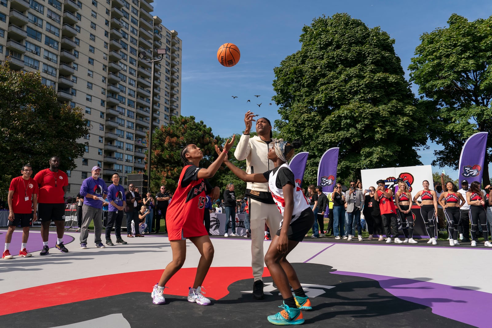 Former Toronto Raptors player Vince Carter, center, throws an opening tip off during the NBA basketball team's unveiling of the revitalized Vince Carter Court in Dixon Park in Toronto, Friday, Sept. 27, 2024. (Paige Taylor White/The Canadian Press via AP)