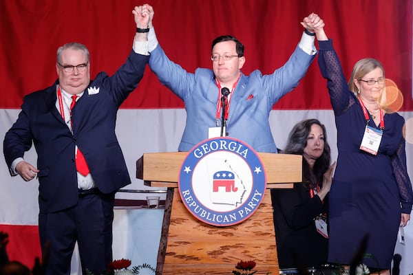 Georgia Republican Party Chairman candidates Dennis Fucch (left) and Rebecca Yardley (right) hold hands with newly appointed chairman Joshua McKoon (center) during the GOP Convention on Saturday, June 10, 2023. (Natrice Miller/The Atlanta Journal-Constitution)