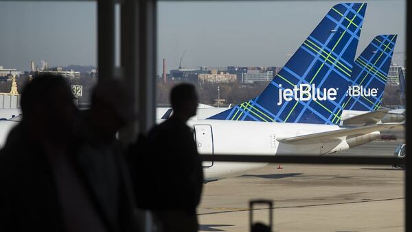 Travelers walk past the tails of JetBlue airplanes in the airport terminal at Ronald Reagan Washington National Airport in Arlington, Virginia. (SAUL LOEB/AFP/Getty Images)