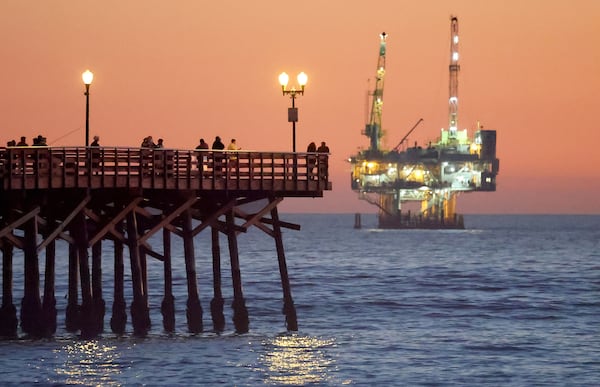 People stand on the the pier with offshore oil and gas platform Esther in the distance on Jan. 5, 2025, in Seal Beach, Calif. President Donald Trump is expected to open more areas to oil drilling, which has worried some on the Georgia coast. (Mario Tama/Getty Images/TNS)