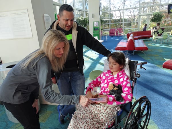 Fish 104.7 afternoon jock Beth Bacall meets with Luis Santillana of Lawrenceville and his 9-year-old daughter Rosalina, who just had scoliosis surgery. She grabbed some Valentine's cards and a teddy bear. CREDIT: Rodney Ho/rho@ajc.com