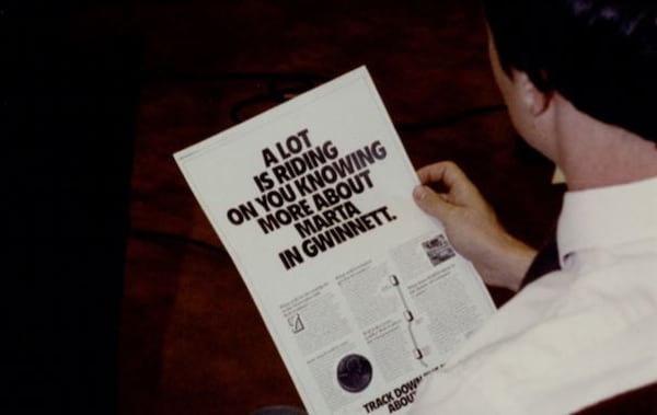 In this 1990 file photo, a Gwinnett resident looks at an ad promoting MARTA expansion into the suburban county. Voters later rejected the expansion. FILE PHOTO