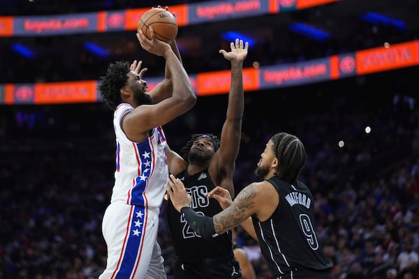 Philadelphia 76ers' Joel Embiid, left, goes up for a shot against Brooklyn Nets' Day'Ron Sharpe, center, and Trendon Watford during the second half of an NBA basketball game, Saturday, Feb. 22, 2025, in Philadelphia. (AP Photo/Matt Slocum)