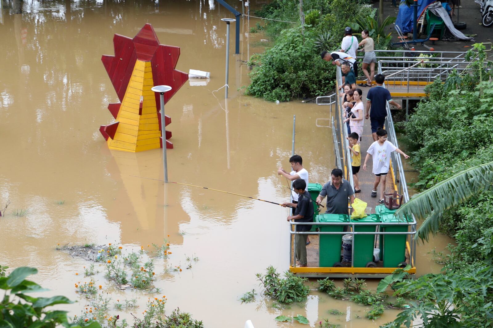 People fish next to a submerged playground due to flood , following Typhoon Yagi in Hanoi, Vietnam on Tuesday, Sept. 10, 2024. (AP Photo/Huy Han)