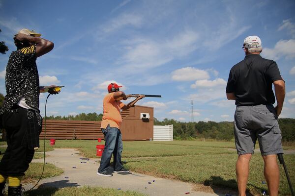 Robert Patillo (center) aims his rifle at a clay pigeon at the Tom Lowe Trap and Skeet Range. (Max Blau / For The Atlanta Journal-Constitution)