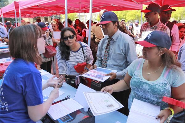 Stephanie Ali of New American Pathways, left, registers newly sworn in citizens to vote. BOB ANDRES /BANDRES@AJC.COM