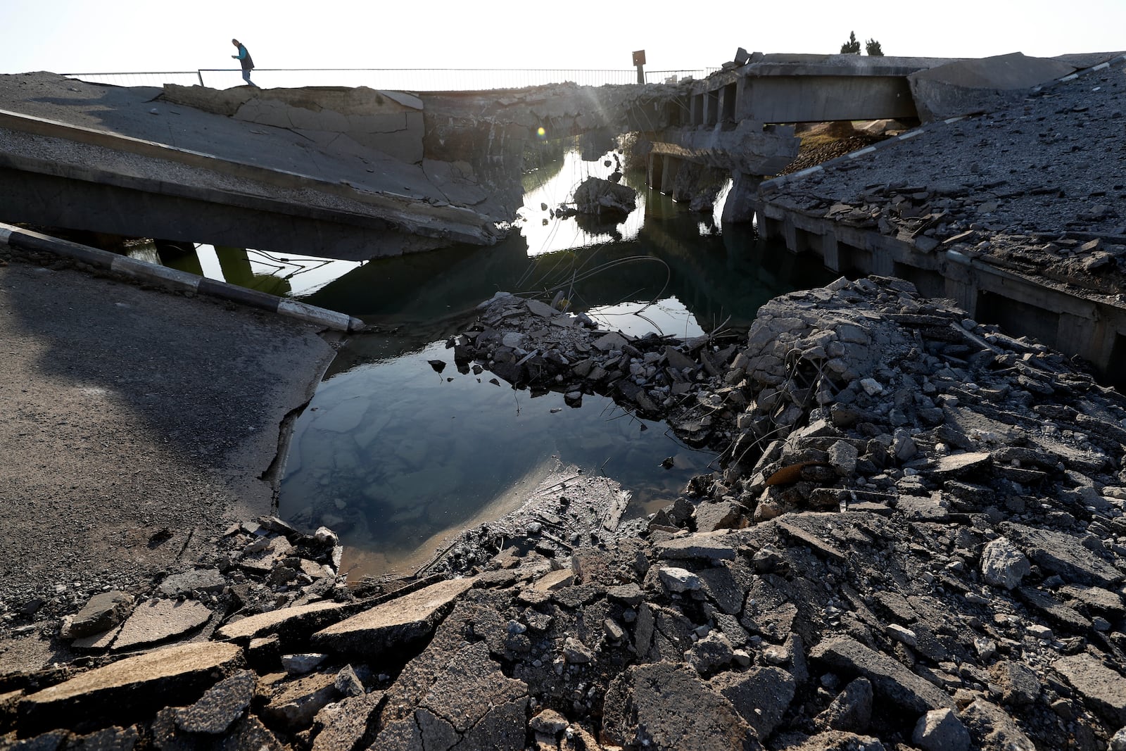 A Syrian man passes by a bridge that links to Lebanon which was destroyed on Oct. 24 by an Israeli airstrike, in Qusair, Syria, Sunday, Oct. 27, 2024. (AP Photo/Omar Sanadiki)