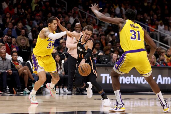 Atlanta Hawks guard Trae Young (11) drives against Los Angeles Lakers forward Juan Toscano-Anderson (95) and  center Thomas Bryant (31) during the second half at State Farm Arena, Friday, Dec. 30, 2022, in Atlanta. The Lakers won 130-121. (Jason Getz / Jason.Getz@ajc.com)