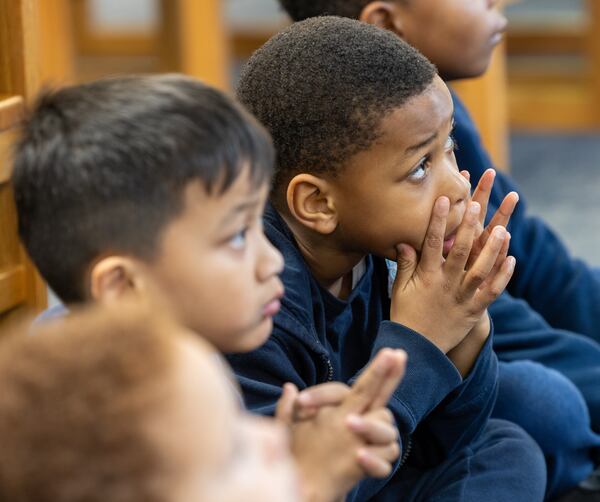 Mj Seneya listens to volunteer Rosemary Schleicher read a book to a group of pre-K and kindergarten students in the Saint Peter Claver Regional Catholic School library. At Saint Peter Claver Regional Catholic School, volunteers tutor and support the students and staff. PHIL SKINNER FOR THE ATLANTA JOURNAL-CONSTITUTION