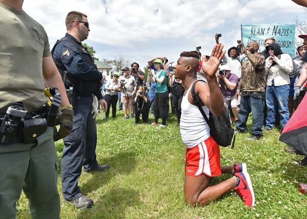 A counterprotester kneels with his hands up in front of law enforcement officers during a neo-Nazi rally at Greenville Street Park in downtown Newnan on Saturday, April 21, 2018. (HYOSUB SHIN / AJC)