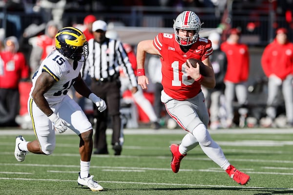 Ohio State quarterback Will Howard, right, scrambles away from Michigan linebacker Ernest Hausmann during the first half of an NCAA college football game Saturday, Nov. 30, 2024, in Columbus, Ohio. (AP Photo/Jay LaPrete)