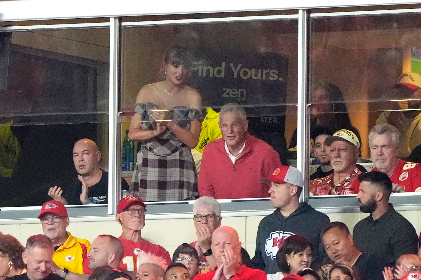 Taylor Swift stands as she watches from a suite next to her dad Scott Swift during the first half of an NFL football game between the Kansas City Chiefs and the New Orleans Saints Monday, Oct. 7, 2024, in Kansas City, Mo. (AP Photo/Charlie Riedel)