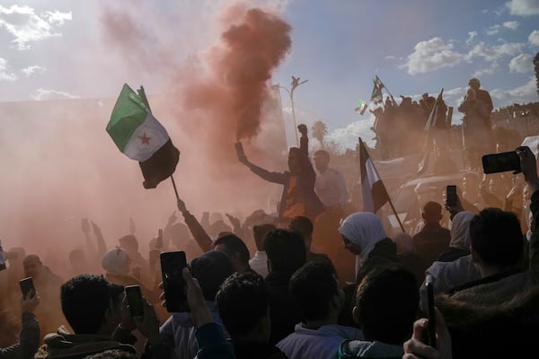 A man waves a flare during a celebratory demonstration following the first Friday prayers since Bashar Assad's ouster, in Damascus' central square, Syria, Friday, Dec. 13, 2024. (AP Photo/Leo Correa)